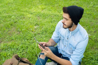 Genç latin adam açık havada tablet kullanma.