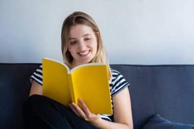 Evde kitap okuyan bir kadın.