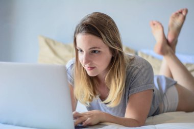 Genç kadın yatakta onu laptop kullanma