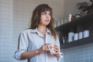 Genç bayan evde kahve içiyor.