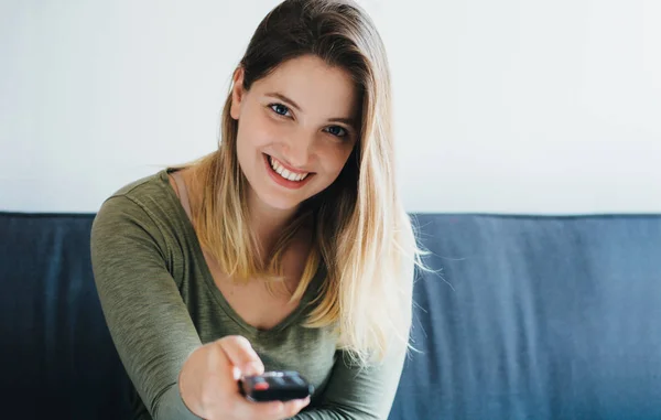 Hermosa mujer sentada en el sofá y viendo la televisión —  Fotos de Stock