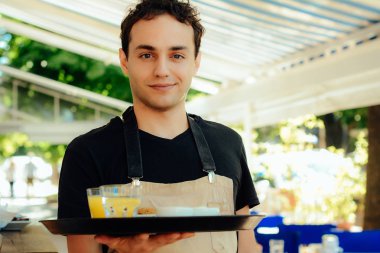 Genç garson holding tepsi.