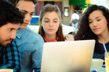 Bir kahve dükkanında bir dizüstü bilgisayar ile toplantı arkadaşlar.