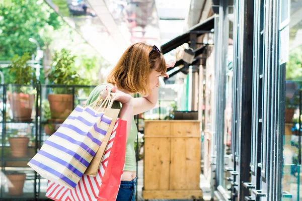 도시에서 쇼핑 백을 가진 젊은 빨간 머리 여자. — 스톡 사진