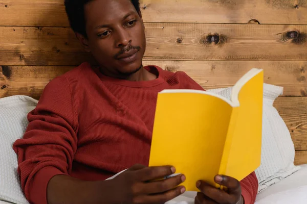 Hombre acostado en la cama y leyendo libro — Foto de Stock