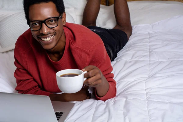Jeune homme utilisant son ordinateur portable au lit — Photo