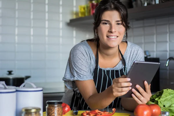 Woman cooking and following recipe on tablet pc