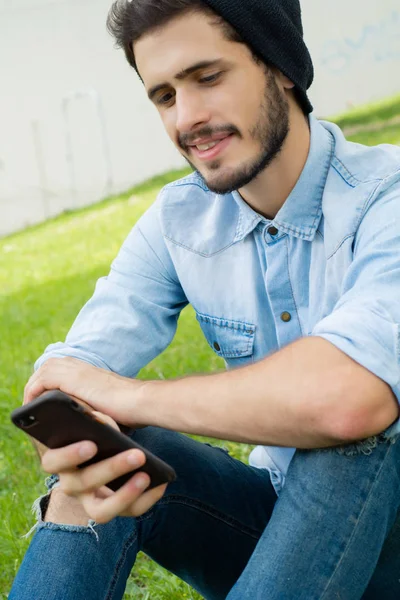 Young man using his phone. Outdoors. — Stock Photo, Image