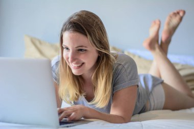 Genç kadın yatakta onu laptop kullanma