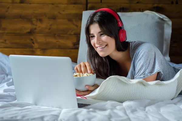 Женщина ест попкорн и смотрит фильмы в постели — стоковое фото