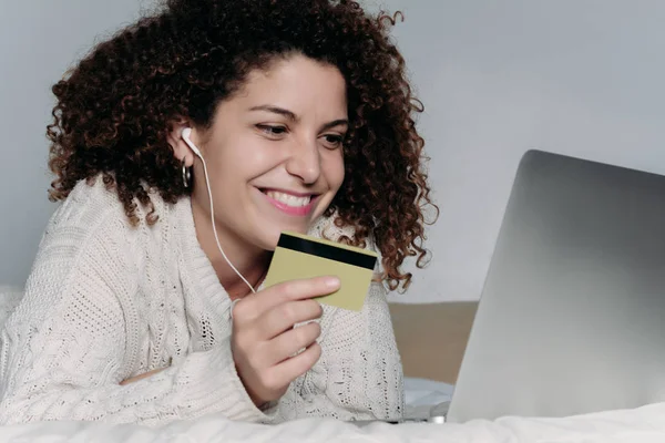 Νεαρή γυναίκα με φορητό υπολογιστή και την πιστωτική κάρτα στο κρεβάτι — Φωτογραφία Αρχείου