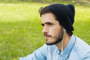 Genç adam kulaklıkla müzik dinliyor.