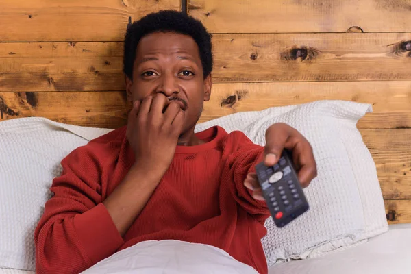 Young man watching tv on bed at home.