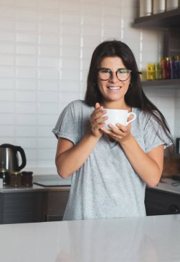 Genç bayan evde kahve içiyor.