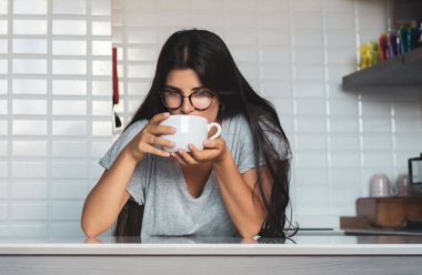 Genç bayan evde kahve içiyor.