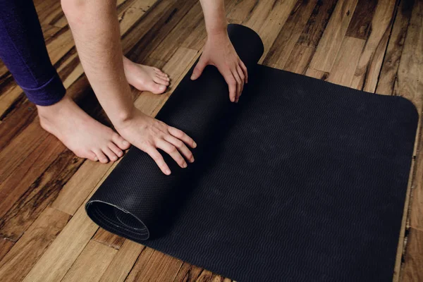 Primer plano de la joven mujer rodando su colchoneta de fitness — Foto de Stock