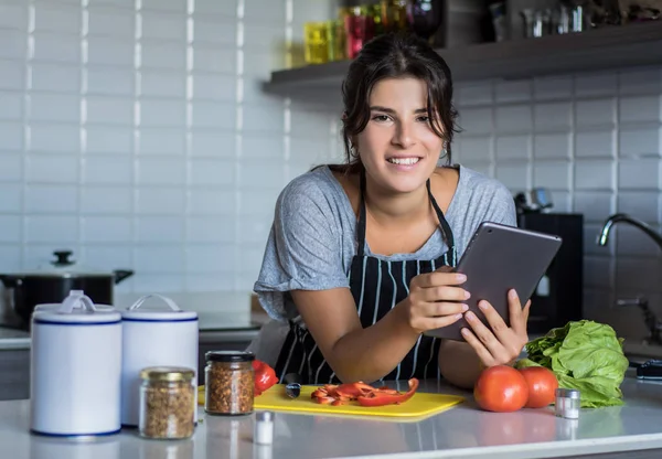 Woman cooking and following recipe on tablet pc