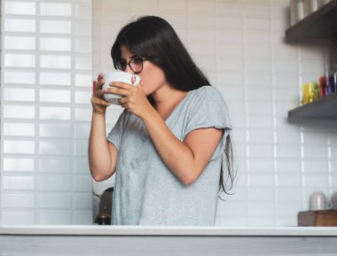 Genç bayan evde kahve içiyor.