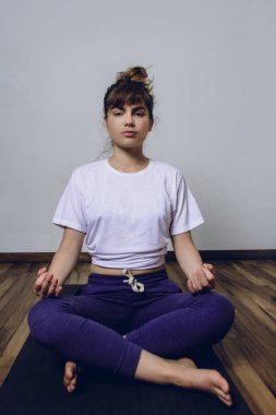 Kadın, Mudra 'yla yarım Lotus pozu vererek yoga yapıyor.