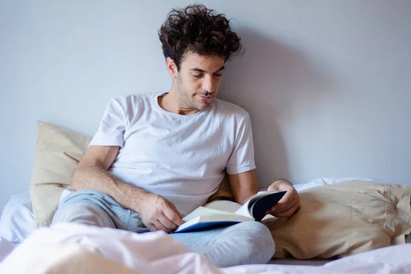Άνθρωπος, διαβάζοντας ένα βιβλίο στο κρεβάτι — Φωτογραφία Αρχείου