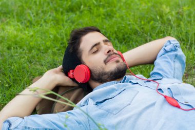 Genç adam rahatlatıcı ve çim müzik dinlerken.