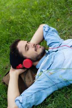 Genç adam rahatlatıcı ve çim müzik dinlerken.