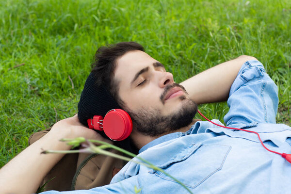 Young man relaxing and listening to music on the grass.