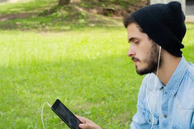 Genç latin adam açık havada tablet kullanma.