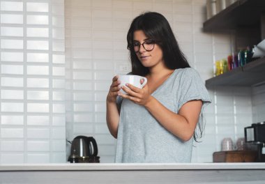 Genç bayan evde kahve içiyor.