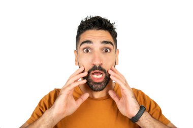 Şok olmuş yüz ifadesi olan ve beyaz arka planda kameraya şaşırmış genç bir adamın portresi..