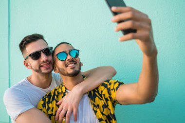 Mutlu eşcinsel çiftin portresi. Birlikte zaman geçirip cep telefonuyla selfie çekiyorlar. Lgbt ve Aşk Konsepti.