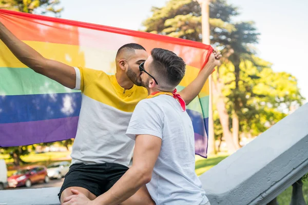 若いゲイのカップルの肖像画がキスし 通りに虹の旗で彼らの愛を示しています Lgbtと愛の概念 — ストック写真