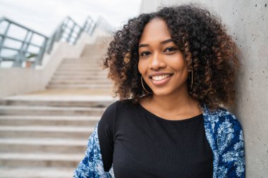Dışarıdaki beton merdivenlerde duran kıvırcık saçlı güzel Afro-Amerikan kadının portresi.. 