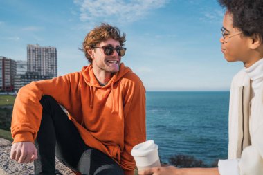 İki genç arkadaşın portresi. Birlikte iyi vakit geçiriyorlar ve arka planda deniz ile eğleniyorlar..