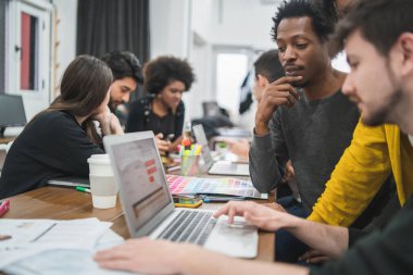 Yaratıcı tasarımcılar bir projede birlikte çalışıyorlar ve işyerleri hakkında yeni fikirleri paylaşıyorlar. İş ve takım çalışması kavramı.
