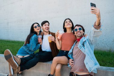 Birlikte eğlenen ve cep telefonuyla selfie çekerken eğlenen bir grup arkadaşın portresi. Yaşam tarzı ve arkadaşlık kavramı.