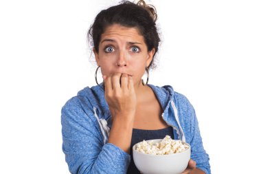 Film izlerken korkmuş görünen ve stüdyoda patlamış mısır yiyen genç bir kadının portresi. İzole edilmiş beyaz arkaplan.