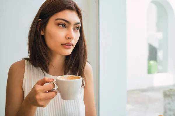 年轻的拉丁女子在咖啡店边喝咖啡边欣赏和喝咖啡的画像 生活方式概念 — 图库照片