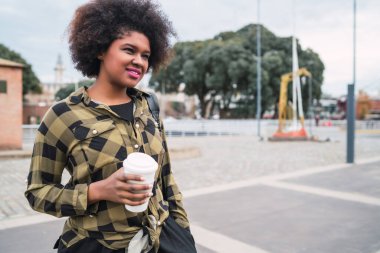 Sokakta elinde bir fincan kahve tutan güzel Afro-Amerikan Latin kadının portresi. Şehir konsepti.