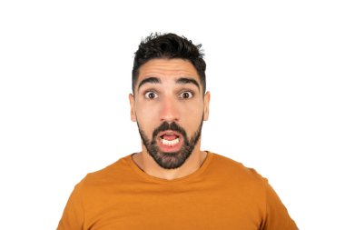 Şok olmuş yüz ifadesi olan ve beyaz arka planda kameraya şaşırmış genç bir adamın portresi..