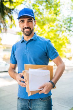 Sokakta paketler ve mektuplar taşıyan bir postacının yakın çekimi. Posta servisi kavramı.