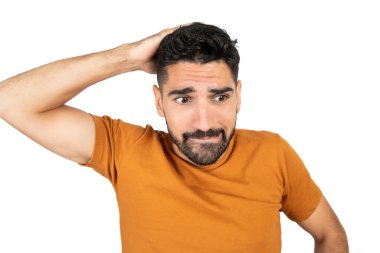 Stüdyoda beyaz arka plana karşı endişeli bir genç adam portresi.