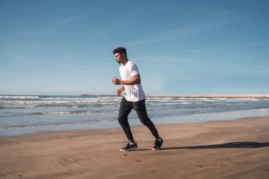 Sahilde koşan atletik bir adamın portresi. Spor, spor ve sağlıklı yaşam tarzı..