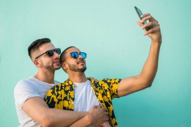 Mutlu eşcinsel çiftin portresi. Birlikte zaman geçirip cep telefonuyla selfie çekiyorlar. Lgbt ve Aşk Konsepti.