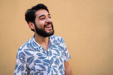 Genç yakışıklı adamın portresi yazdan zevk alıyor ve sarı arka planda yaz kıyafetleri giyiyor.. 