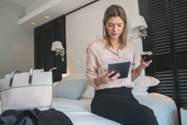 Otel odasında dijital tableti üzerinde çalışan genç iş kadınının portresi. İş seyahati kavramı.