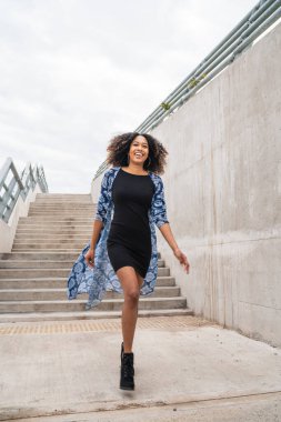 Dışarıdaki merdivenlerde yürüyen kendinden emin Afro-Amerikan bir kadının portresi..