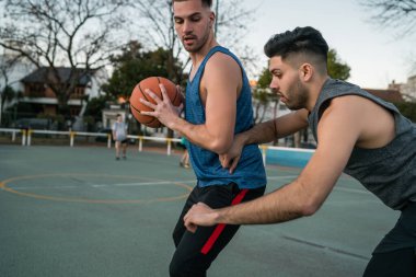 Genç basketbolcular dışarıda teke tek oynuyor. Spor ve basketbol konsepti.