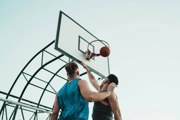 Young basketball players playing one-on-one on outdoor court. Sport and basketball concept.