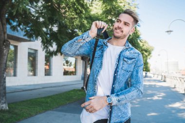 Omuzlarında sırt çantasıyla sokakta yürüyen çekici bir gencin portresi. Şehir konsepti.